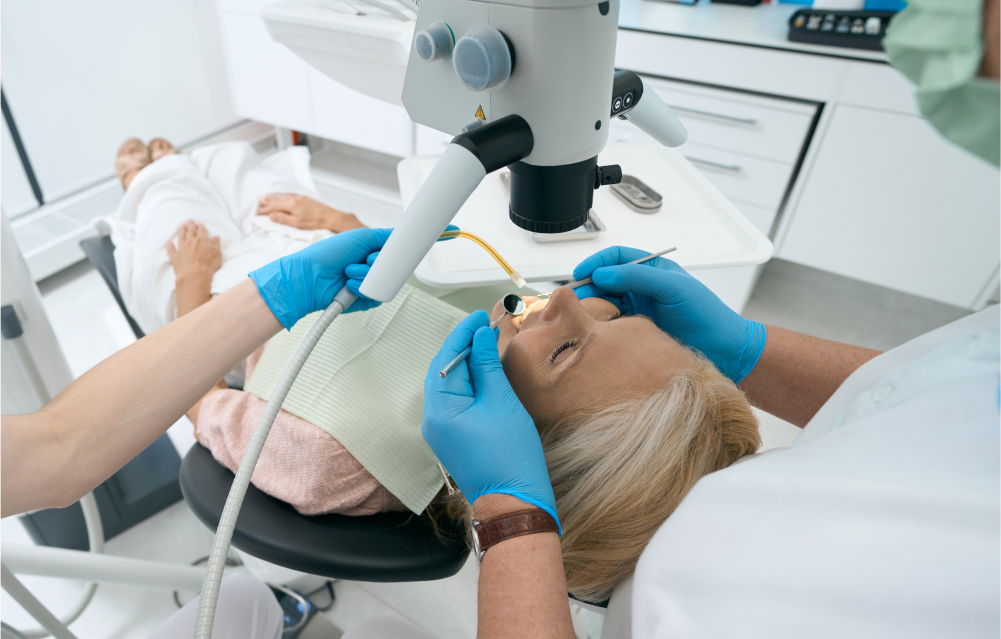 Using a light-emitting device, a dentist examines tissues in the mouth for signs of disease.