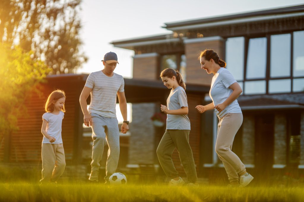 family of four playing soccer in frontyard