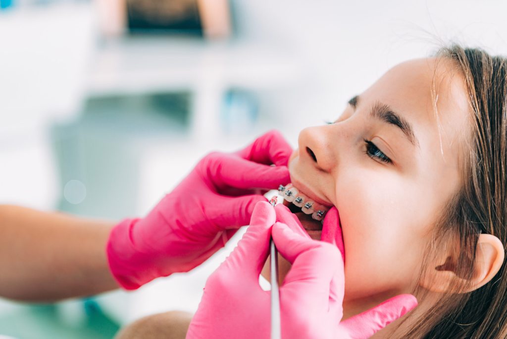 orthodontist checking girls braces in office