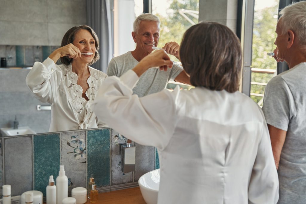 elderly couple brushing teeth in the mirror