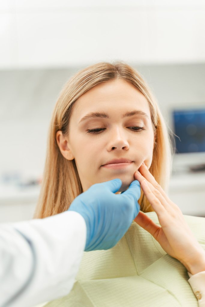 dental patient touching toothache while dentist feels it